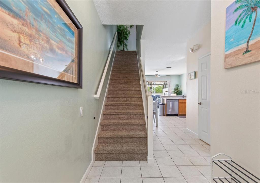 A carpeted staircase leads to an upper level in a home with tiled flooring — 8106 PRINCESS PALM LANE, KISSIMMEE, FL