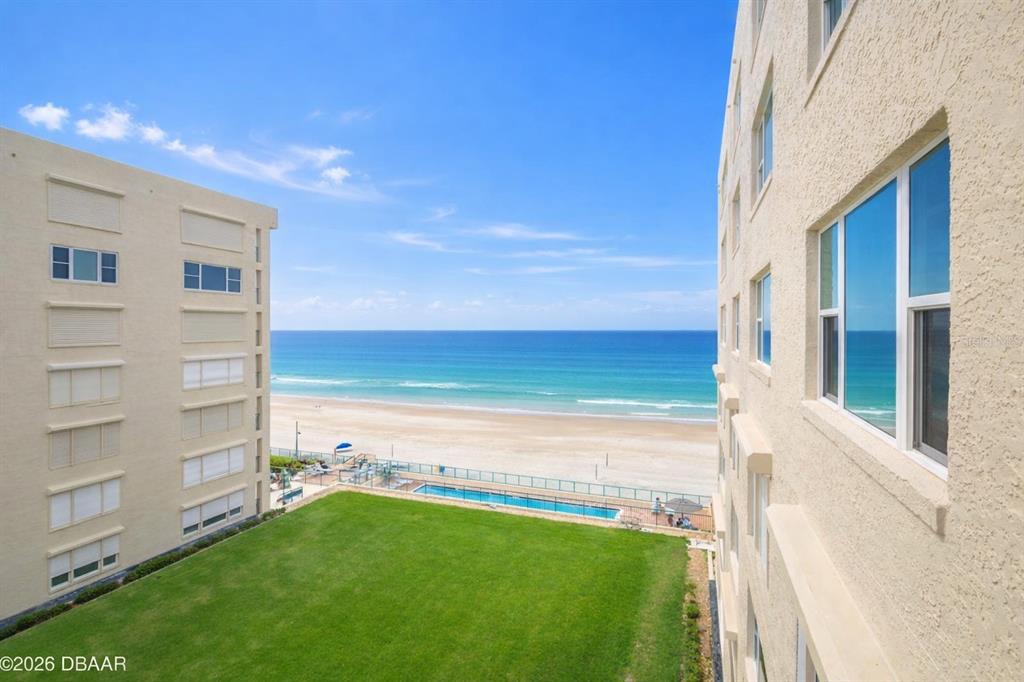An elevated view shows a grassy courtyard, a swimming pool, and the ocean beach — 4575 S ATLANTIC AVENUE UNIT 6502, PORT ORANGE, FL