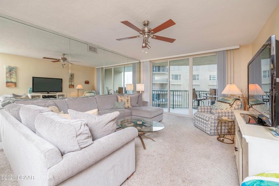 A living room features a large gray sectional sofa, mirrored walls, and a sliding glass door — 4575 S ATLANTIC AVENUE UNIT 6502, PORT ORANGE, FL