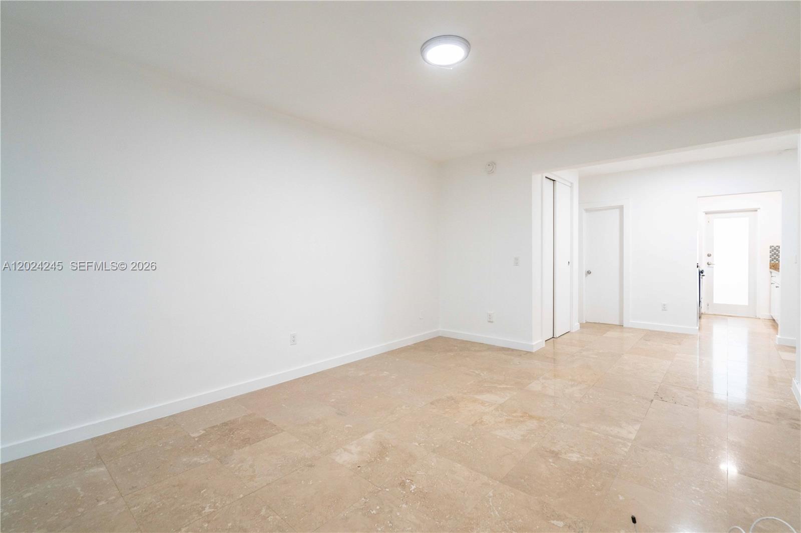 A bright, empty room features white walls, a flush-mount ceiling light, and beige tile flooring — 1120 Euclid Ave # 6, Miami Beach FL 33139, MIAMI BEACH, FL