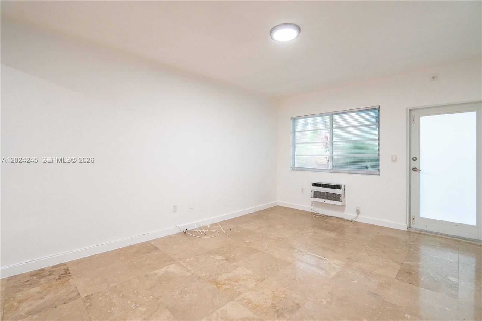 An empty room features white walls, tile flooring, a window with blinds, and an air conditioner — 1120 Euclid Ave # 6, Miami Beach FL 33139, MIAMI BEACH, FL