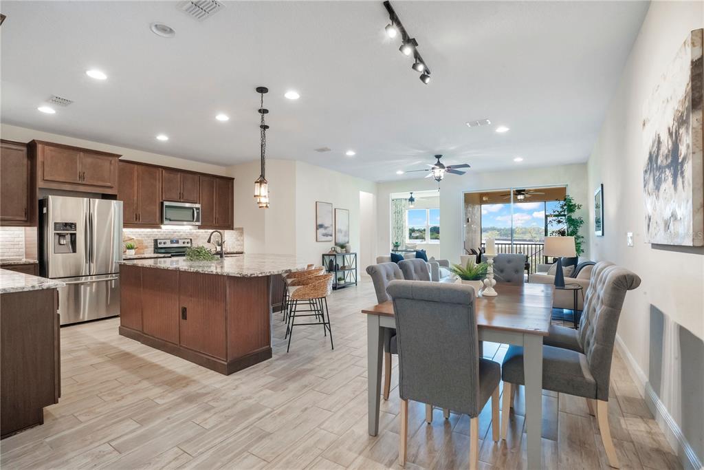 An open-concept kitchen and dining area features wood cabinets, granite countertops, and tile flooring — 9009 PALM KEY AVENUE, OLDSMAR, FL