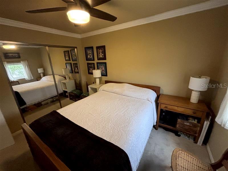 A bedroom features a bed with a white coverlet, a ceiling fan, and mirrored closet doors — 4950 BAYSHORE BOULEVARD UNIT 28, TAMPA, FL