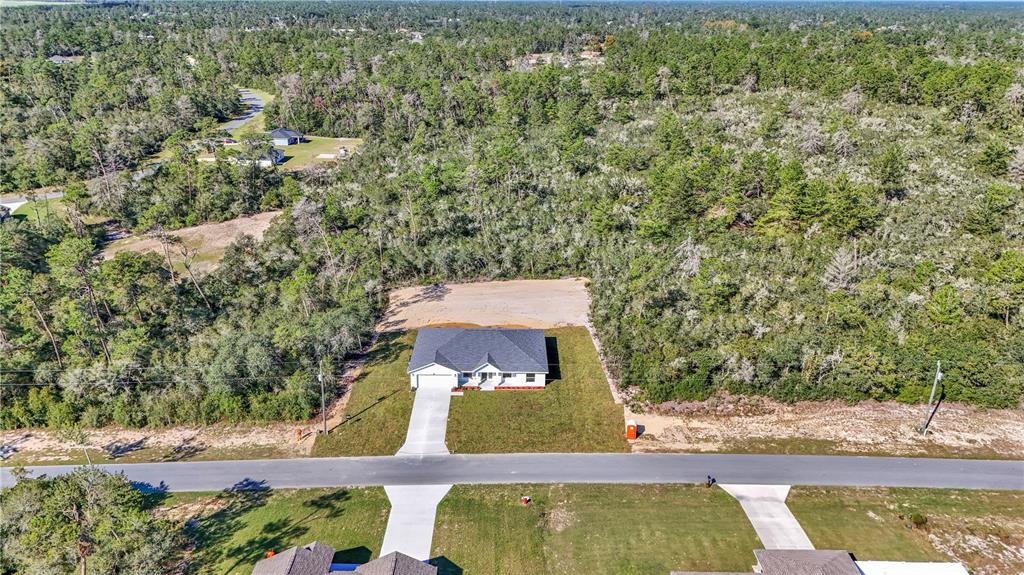 An aerial view shows a single-story house with a driveway surrounded by dense forest — 17694 SW 25 CIRCLE, OCALA, FL
