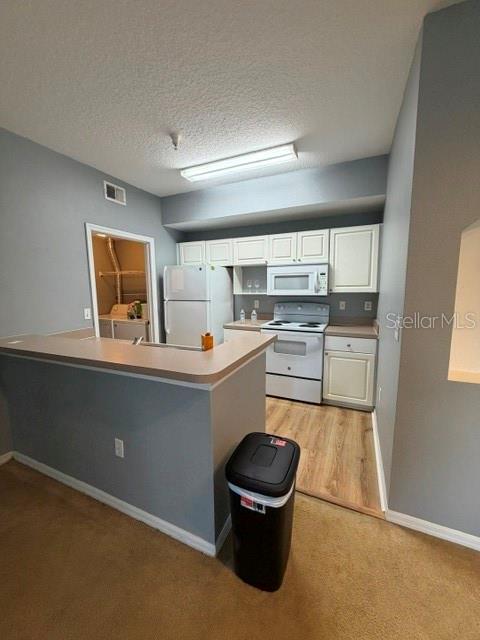 A kitchen features white cabinets, a white refrigerator, a white stove, and a breakfast bar — 5524 METROWEST BOULEVARD UNIT 206, ORLANDO, FL