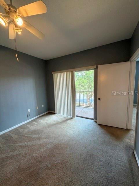 A bedroom with gray walls, beige carpet, a ceiling fan, and a sliding glass door — 5524 METROWEST BOULEVARD UNIT 206, ORLANDO, FL