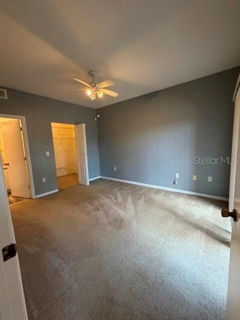 A bedroom with gray walls, beige carpeting, a ceiling fan, and an open walk-in closet — 5524 METROWEST BOULEVARD UNIT 206, ORLANDO, FL