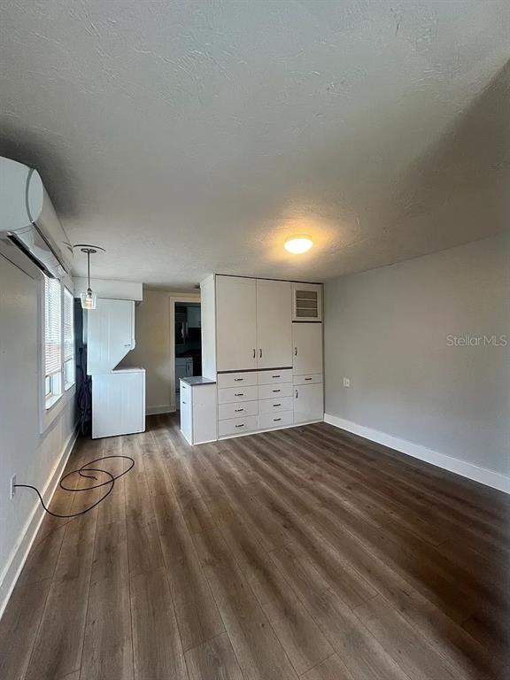 A room with wood-look flooring, white walls, a built-in storage unit, and a laundry area — 1713 29TH STREET W, BRADENTON, FL
