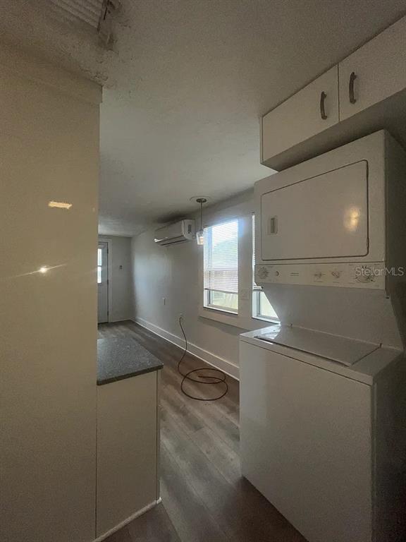A laundry area with a stacked washer and dryer unit next to a hallway — 1713 29TH STREET W, BRADENTON, FL