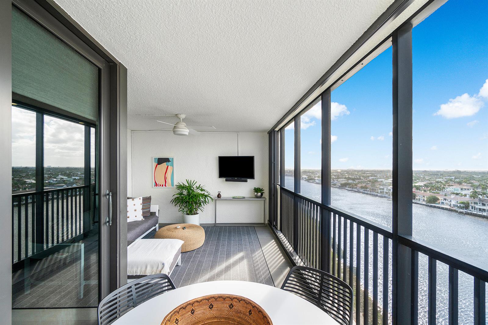 A screened-in balcony features a seating area, a wall-mounted television, and a waterfront view — 3420 S Ocean Boulevard # 14x, Highland Beach FL 33487, HIGHLAND BEACH, FL