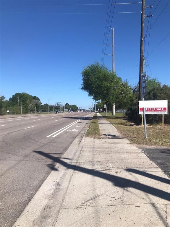 A sidewalk runs alongside a multi-lane road with a lot for sale sign nearby — 5311 24TH STREET COURT E, BRADENTON, FL