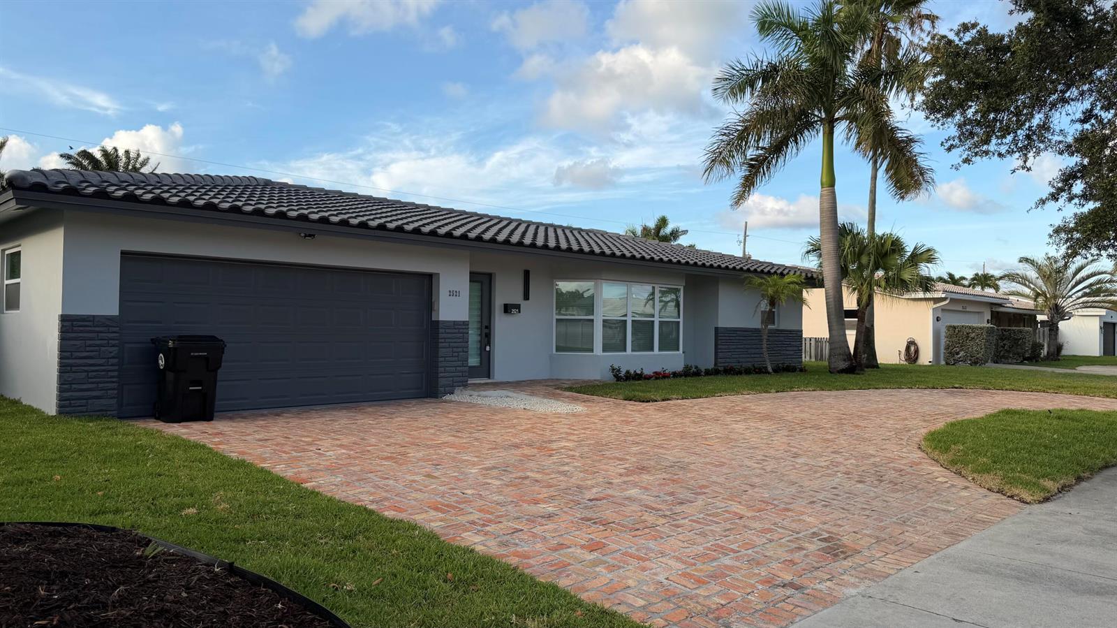 A single-story house with a brick driveway, gray exterior, and a dark tile roof — 2521 NE 45th Street, Lighthouse Point FL 33064, LIGHTHOUSE POINT, FL