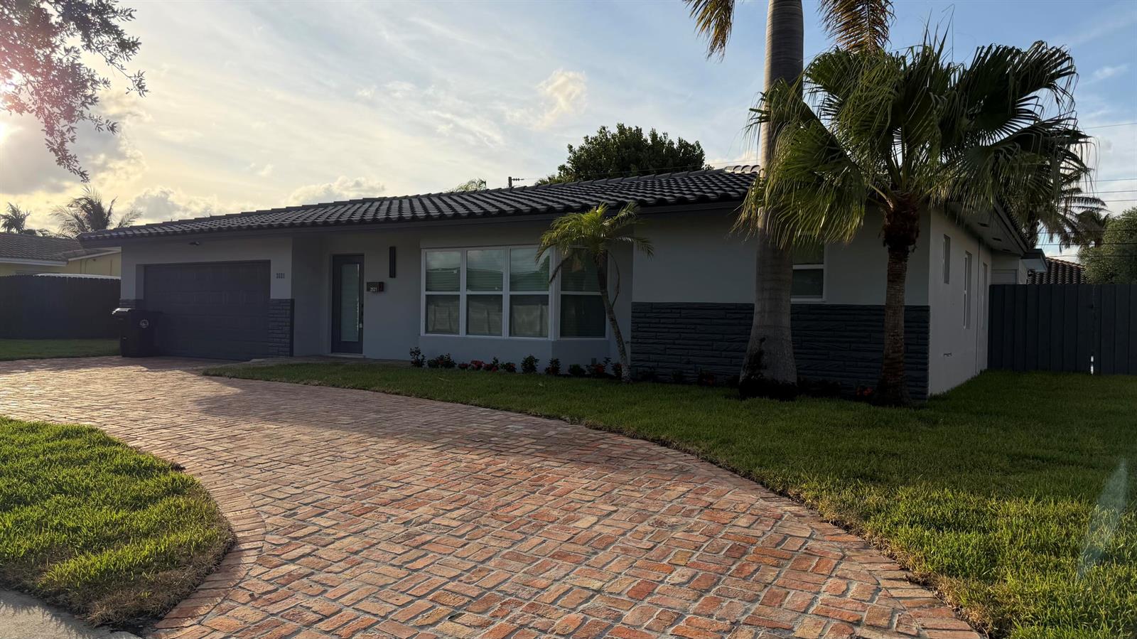 A single-story house with a brick driveway, gray exterior, and a dark tile roof — 2521 NE 45th Street, Lighthouse Point FL 33064, LIGHTHOUSE POINT, FL