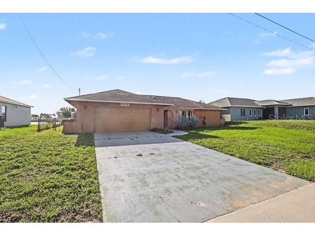 A single-story house with a tan stucco exterior and a concrete driveway — 1219 NE 14TH PLACE, CAPE CORAL, FL