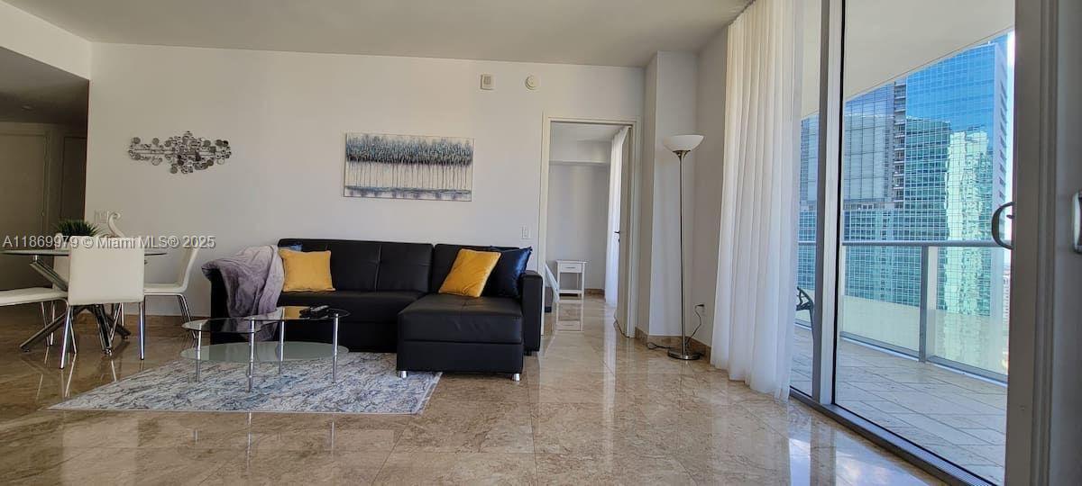 A modern living room features a black sectional sofa, marble floors, and a balcony view — 1300 Brickell Bay Dr # 3007, Miami FL 33131, MIAMI, FL