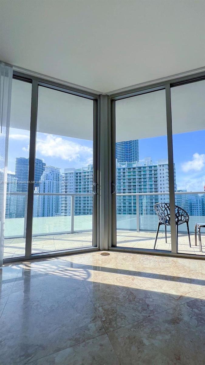 A room with marble floors and floor-to-ceiling windows overlooking a city skyline and balcony — 1300 Brickell Bay Dr # 3007, Miami FL 33131, MIAMI, FL
