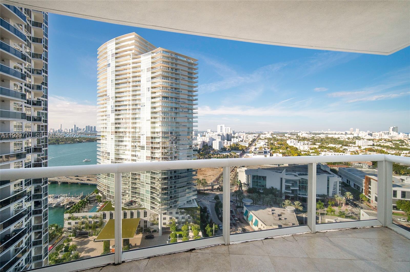 A balcony overlooks a high-rise building, a bay, and a city skyline under a blue sky — 400 Alton Rd # 2309, Miami Beach FL 33139, MIAMI BEACH, FL