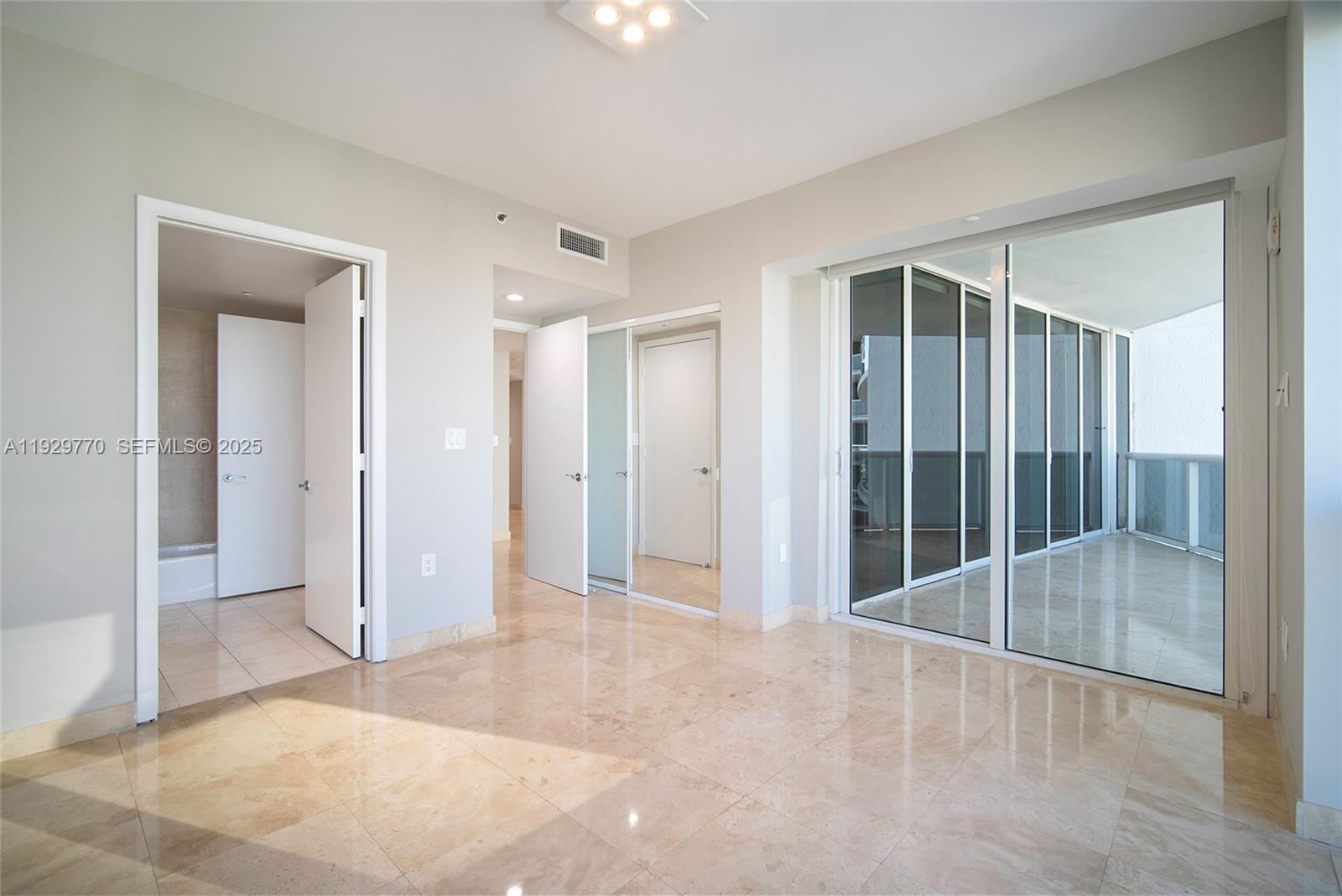 A room with light-colored tile flooring, multiple doorways, and a large sliding glass balcony door — 400 Alton Rd # 2309, Miami Beach FL 33139, MIAMI BEACH, FL