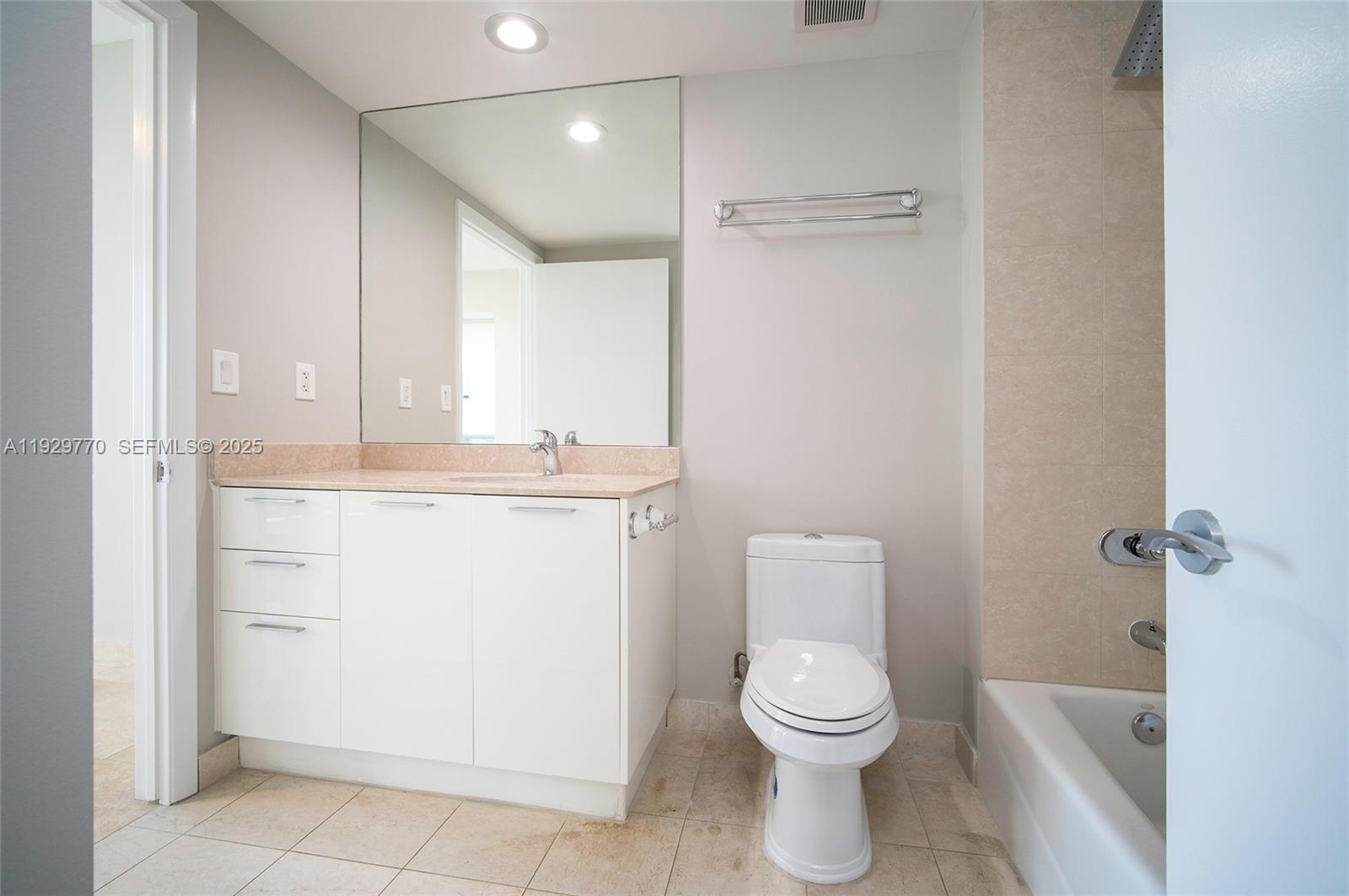 A bathroom features a white vanity, a large mirror, a toilet, and a tiled bathtub — 400 Alton Rd # 2309, Miami Beach FL 33139, MIAMI BEACH, FL