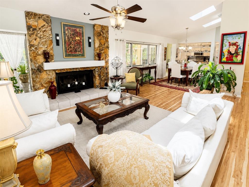 A living room features a stone fireplace, white sofas, a coffee table, and hardwood floors — 9801 DIDRIKSON DRIVE, NEW PORT RICHEY, FL