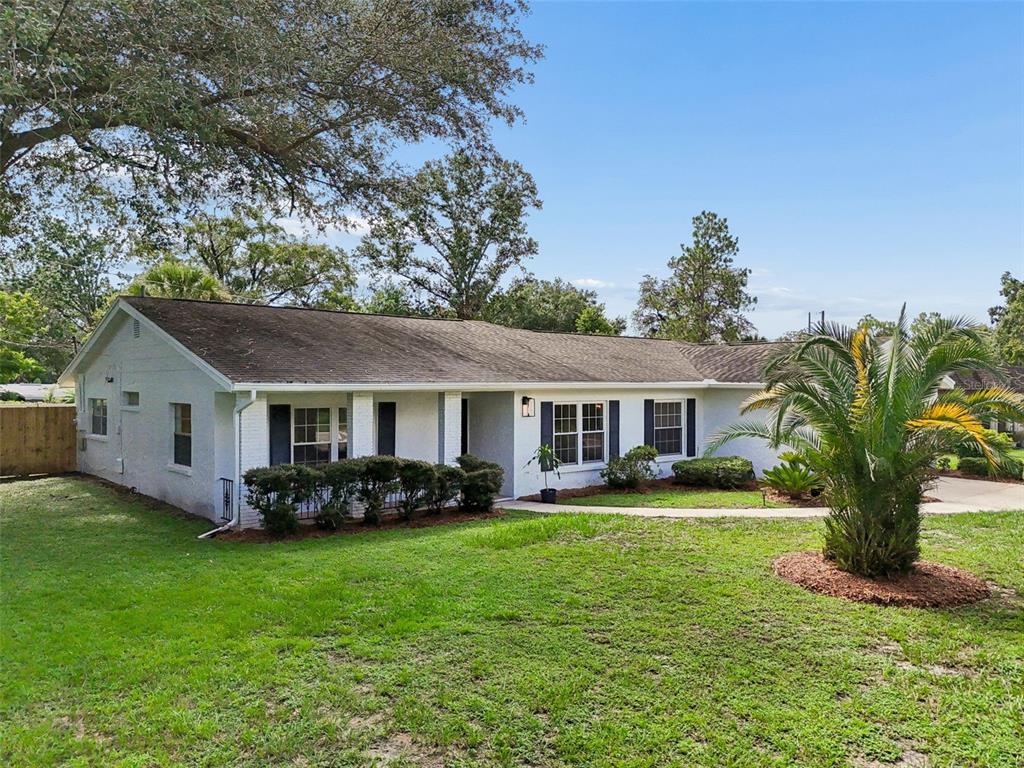 A single-story white brick house with a dark shingled roof and a front palm tree — 507 ROLLINGVIEW DRIVE, TEMPLE TERRACE, FL