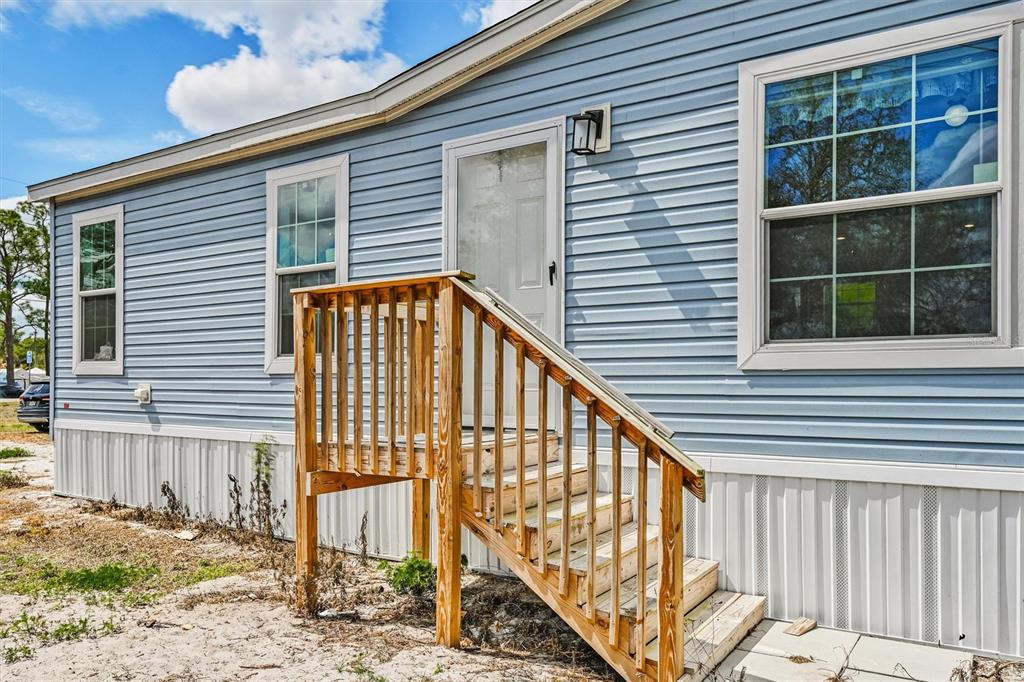 A light blue mobile home exterior features a white door, wooden stairs, and vinyl siding — 1770 TUCKER LANE, NORTH FORT MYERS, FL