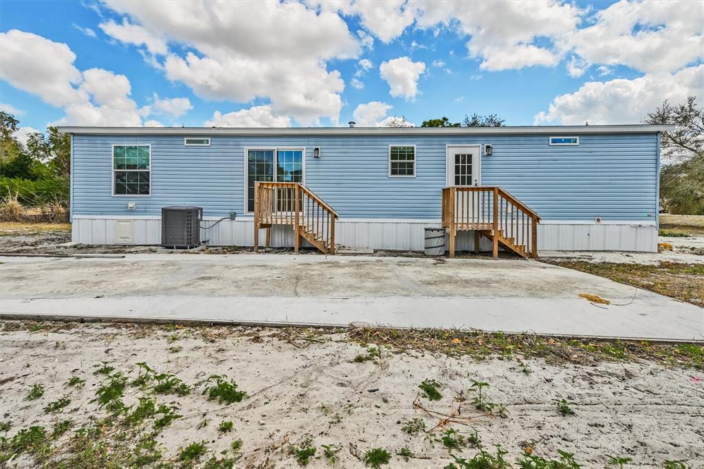 The exterior of a light blue mobile home features two wooden staircases and a concrete pad — 1770 TUCKER LANE, NORTH FORT MYERS, FL