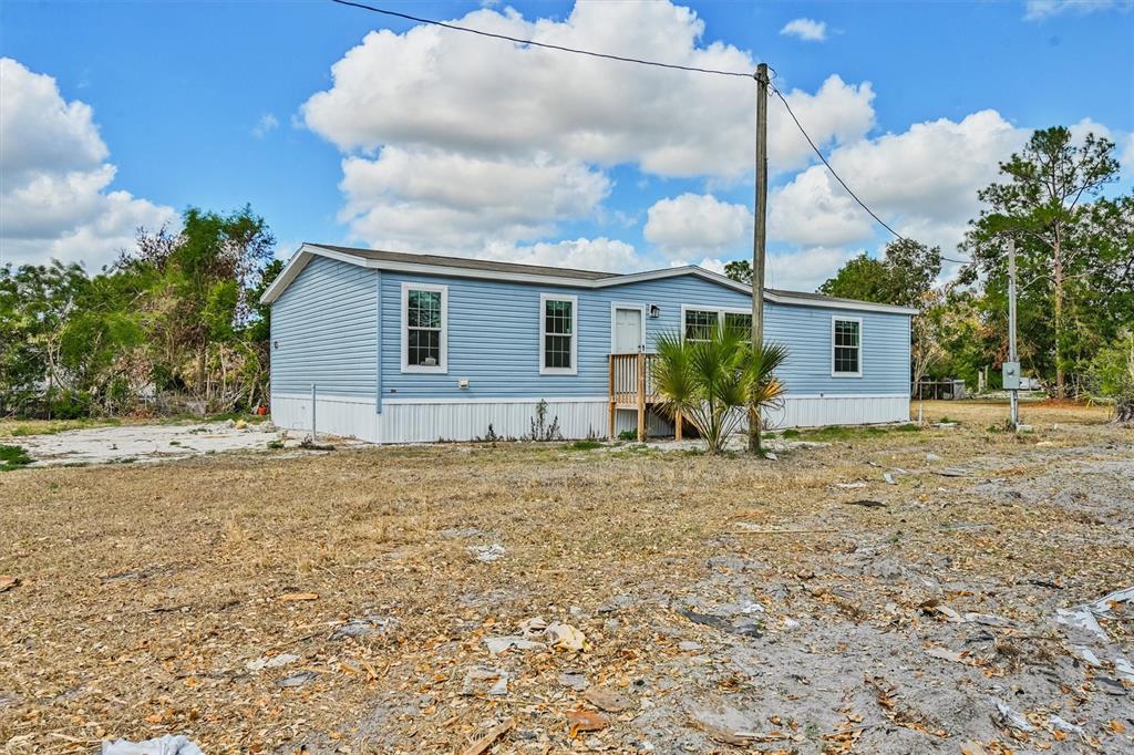 A light blue manufactured home sits on a dry, sparse lot under a cloudy sky — 1770 TUCKER LANE, NORTH FORT MYERS, FL