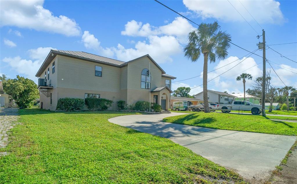 A two-story house with tan siding and a concrete driveway sits on a grassy lot — 2050 NW 18TH STREET, CRYSTAL RIVER, FL