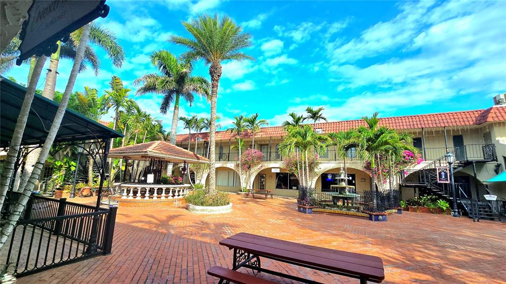 A brick courtyard features a gazebo, a fountain, palm trees, and a two-story building — 530 US-41-BYP UNIT 1A, VENICE, FL