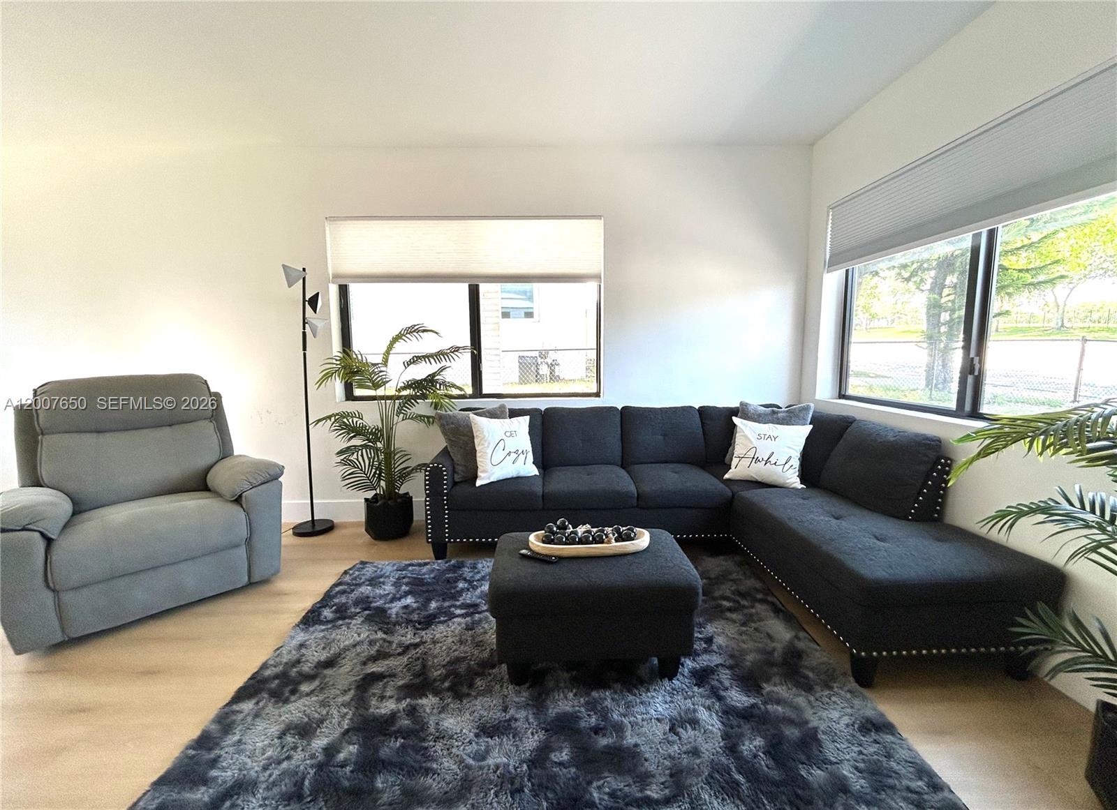 A living room features a dark sectional sofa, a gray recliner, and a shaggy rug — 808 45th St, West Palm Beach FL 33407, WEST PALM BEACH, FL