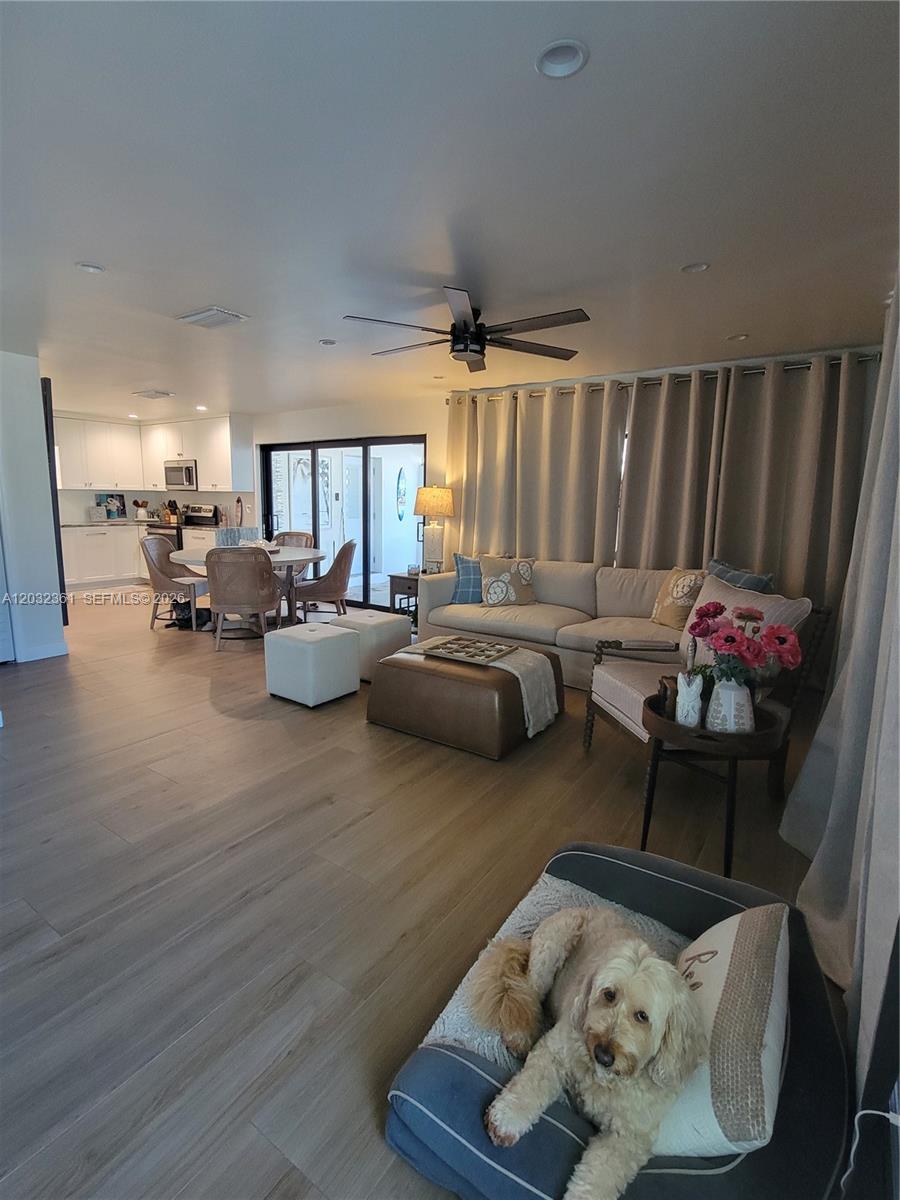 An open-concept living room and kitchen feature light wood flooring, neutral furniture, and a dog — 11339 5th Avenue Ocean, Marathon FL 33050, MARATHON, FL
