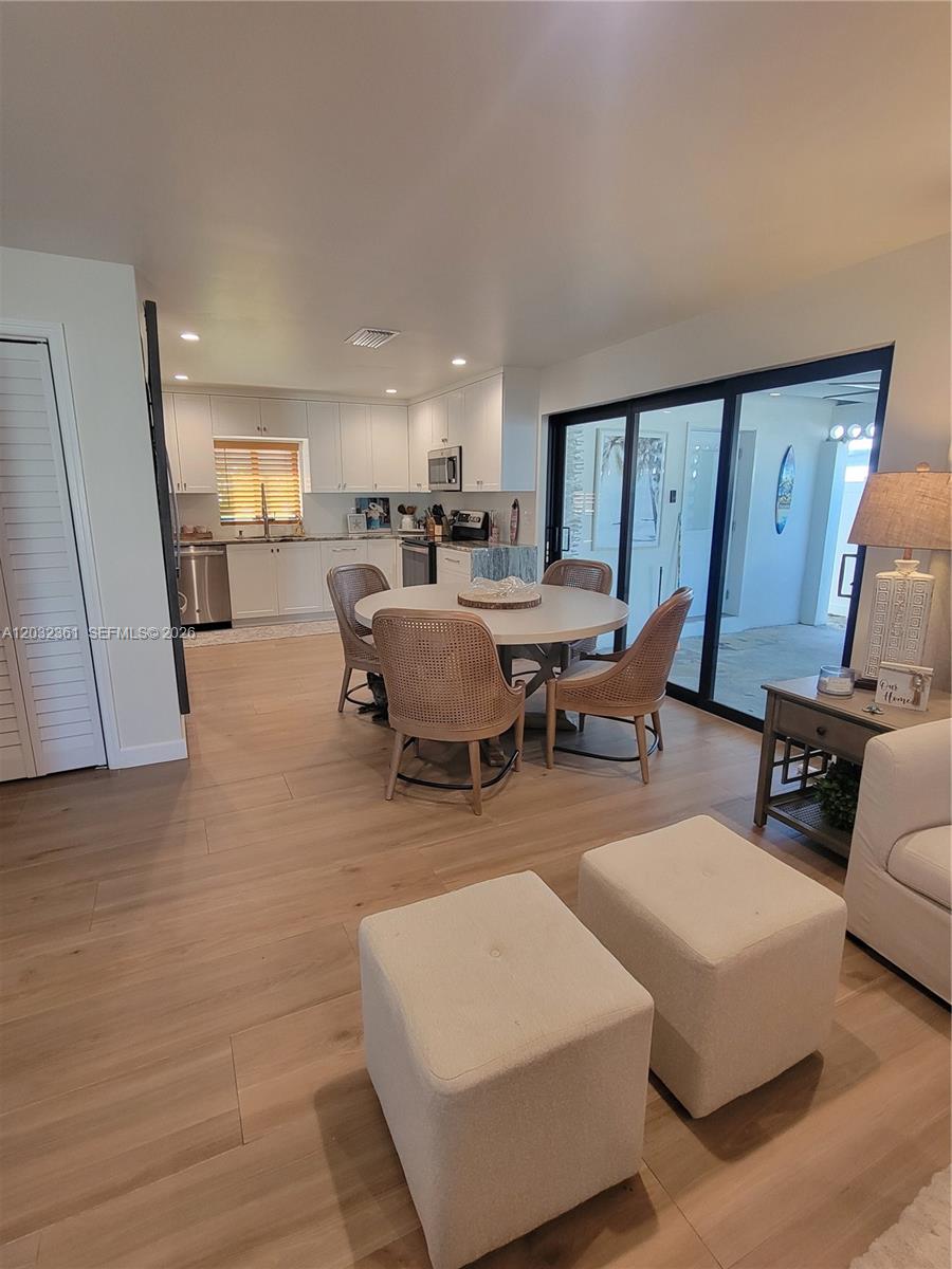 A dining area with a round table and rattan chairs sits adjacent to a white kitchen — 11339 5th Avenue Ocean, Marathon FL 33050, MARATHON, FL