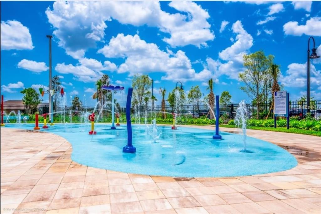 A blue splash pad with water features and fountains sits outdoors on a sunny day — 4741 CLOCK TOWER DRIVE UNIT 208, KISSIMMEE, FL