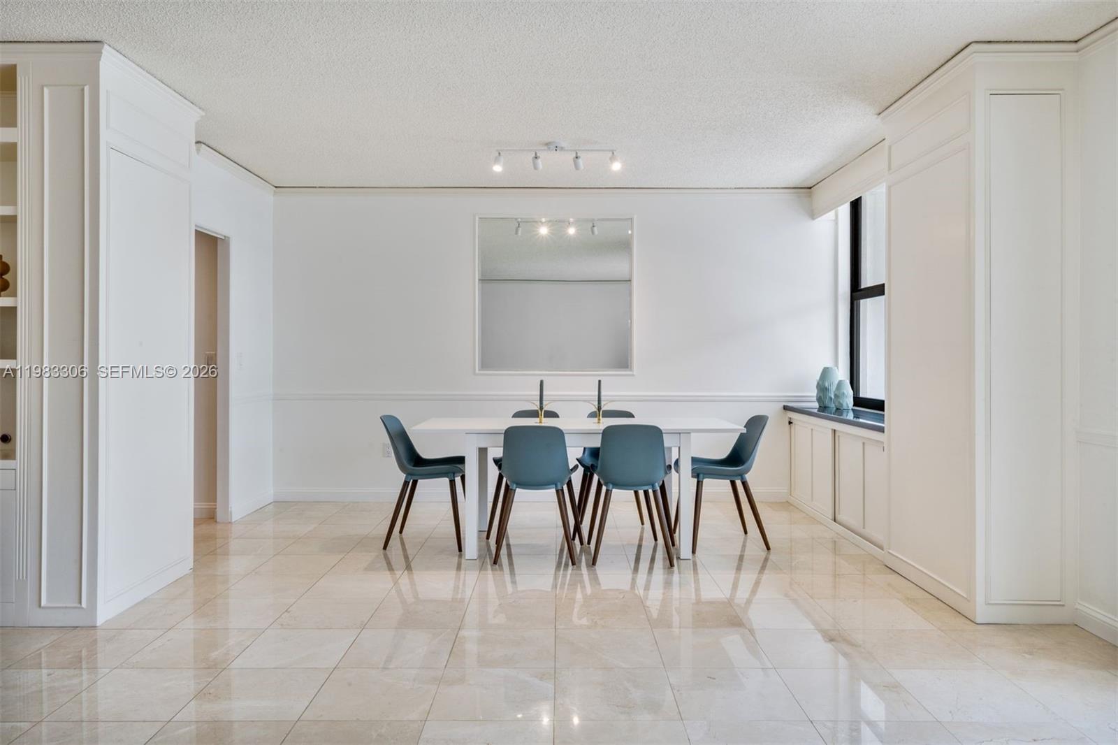 A dining room features a white table with six blue chairs, a mirror, and tile flooring — 9801 Collins Ave # 19H, Bal Harbour FL 33154, BAL HARBOUR, FL
