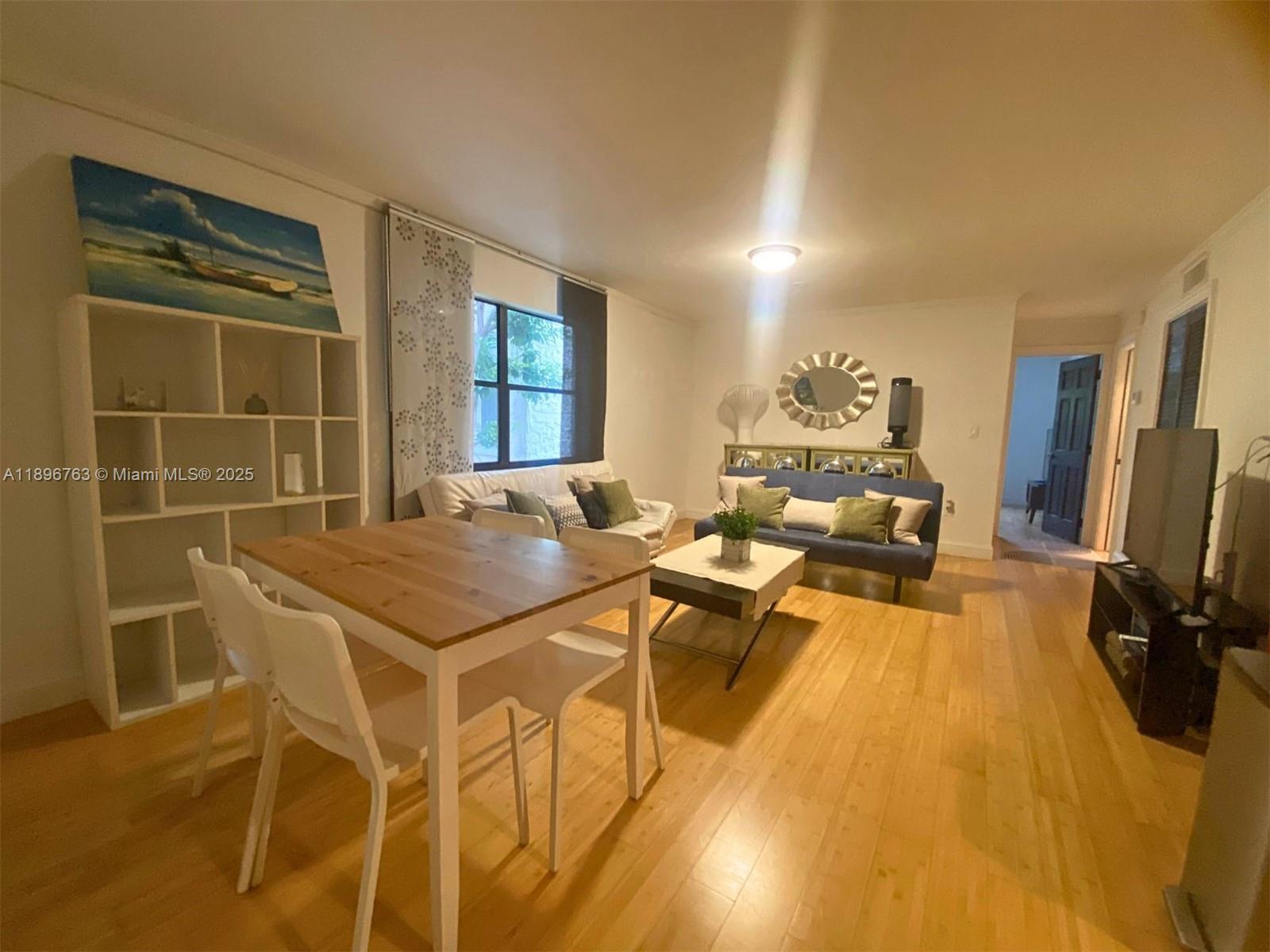 A living room with light wood floors, a dining table, and a blue sofa — 753 Michigan Ave # 2B, Miami Beach FL 33139, MIAMI BEACH, FL