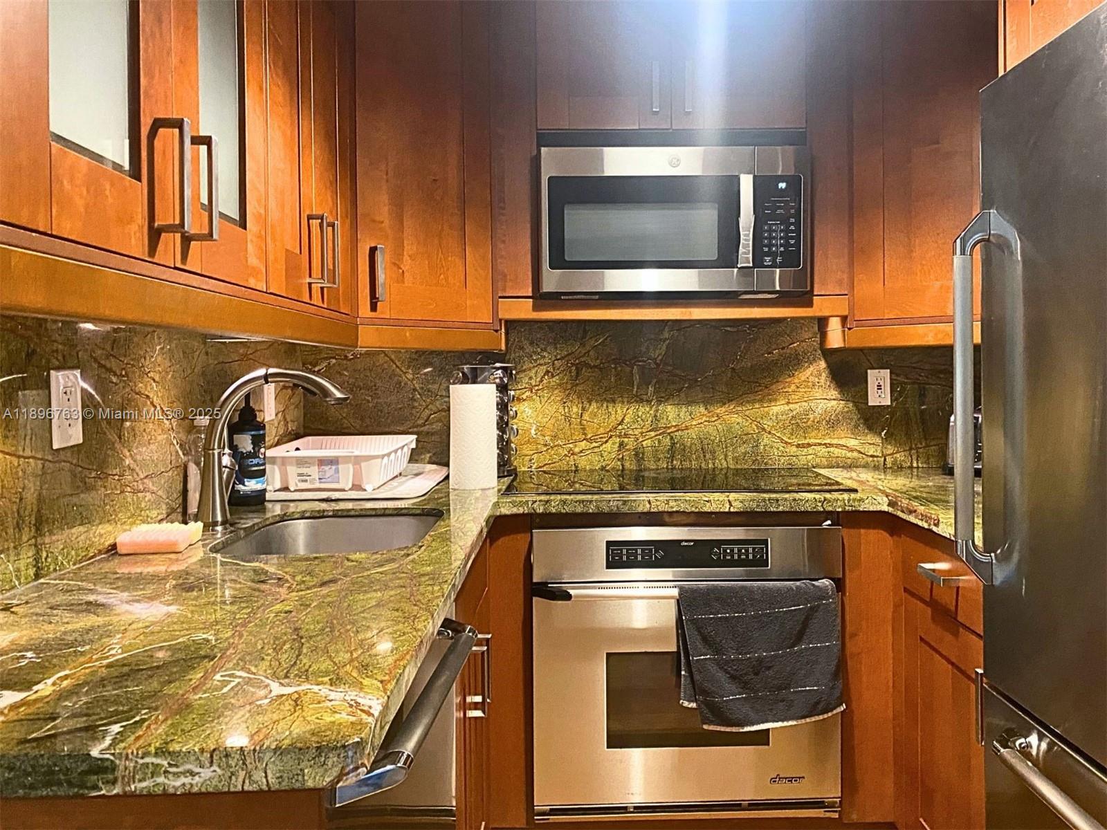 A kitchen features wood cabinets, stainless steel appliances, and green stone countertops and backsplash — 753 Michigan Ave # 2B, Miami Beach FL 33139, MIAMI BEACH, FL