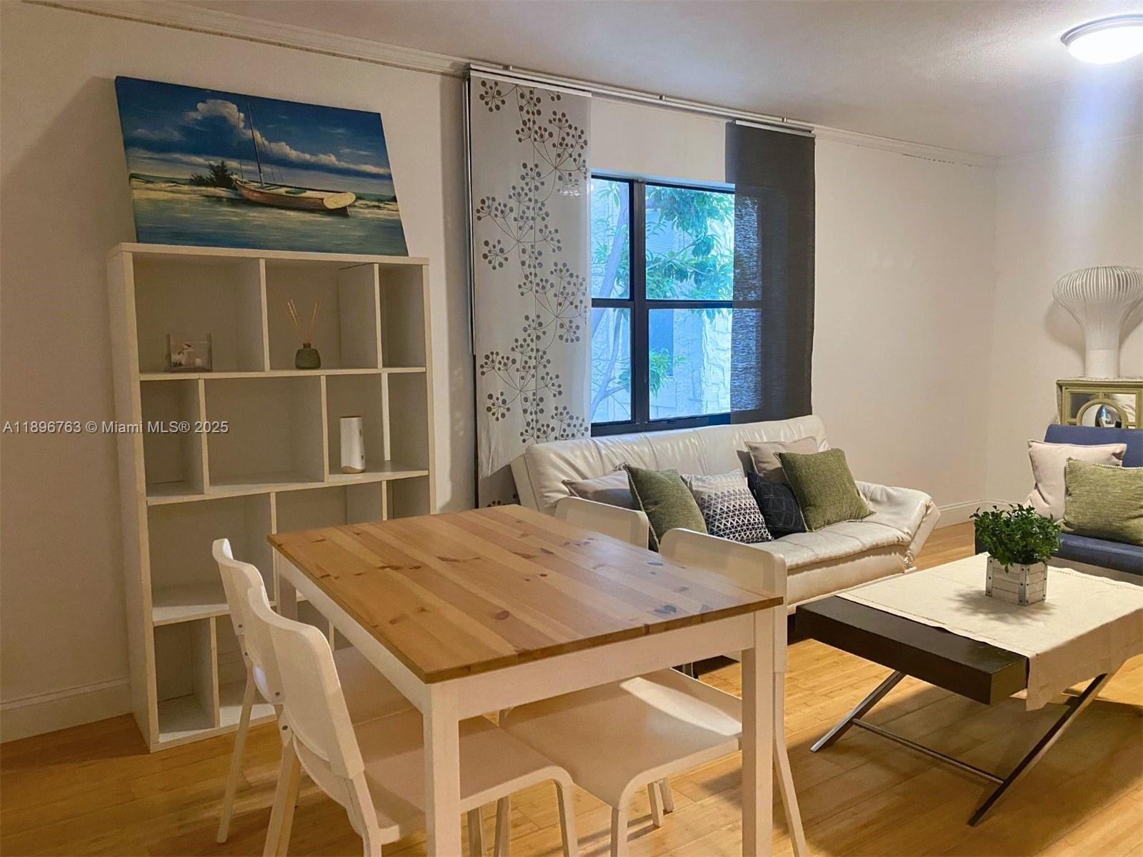 A living and dining area features a wooden table, white shelving, and a white sofa — 753 Michigan Ave # 2B, Miami Beach FL 33139, MIAMI BEACH, FL