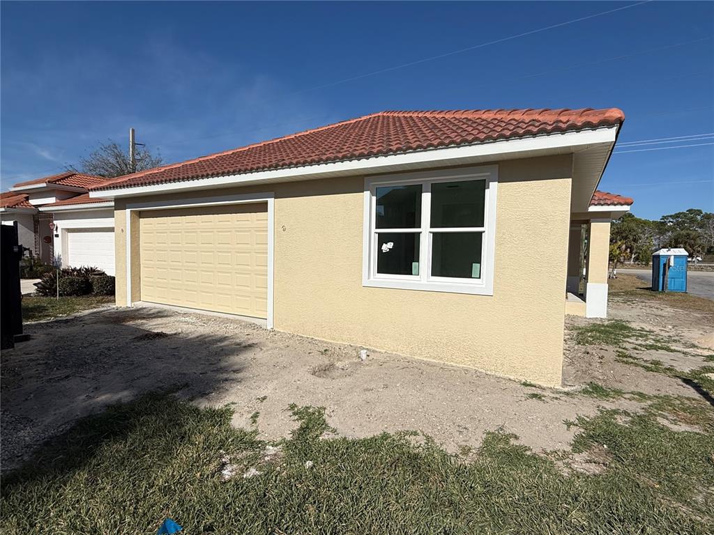 A tan, single-story house exterior features a garage, a window, and a red tile roof — 0 SORRENTO PLACE, NOKOMIS, FL