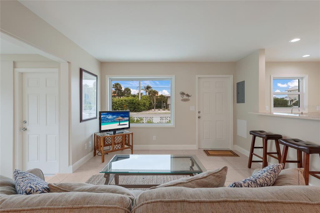 A living room features a glass coffee table, a television on a stand, and tile flooring — 320 GULF BOULEVARD UNIT 1A, BOCA GRANDE, FL