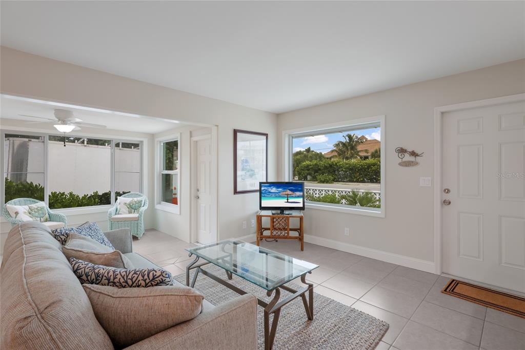 A living room features tile flooring, a glass coffee table, a sofa, and large windows — 320 GULF BOULEVARD UNIT 1A, BOCA GRANDE, FL