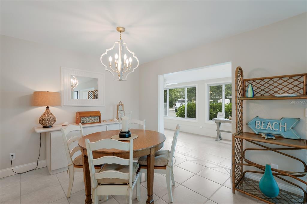 A dining room features a round wooden table, white chairs, a chandelier, and a shelving unit — 320 GULF BOULEVARD UNIT 1A, BOCA GRANDE, FL