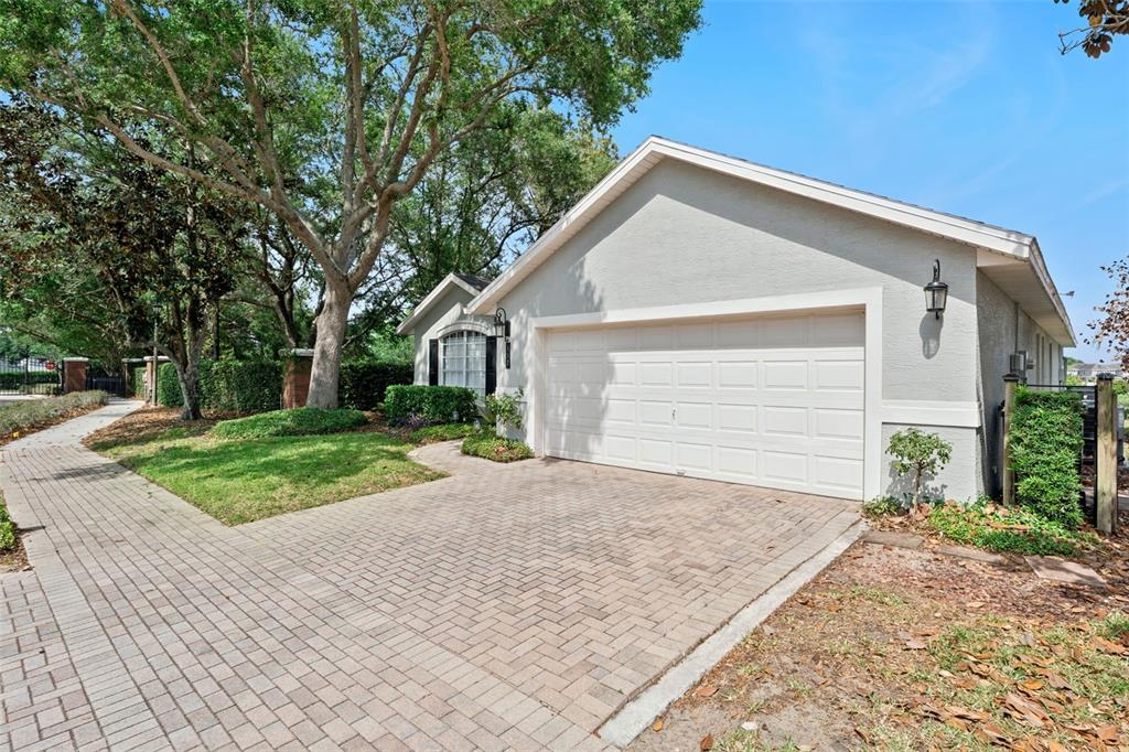 A single-story house with a white garage door and a brick paver driveway — 112 WINDSOR PLACE, DAVENPORT, FL