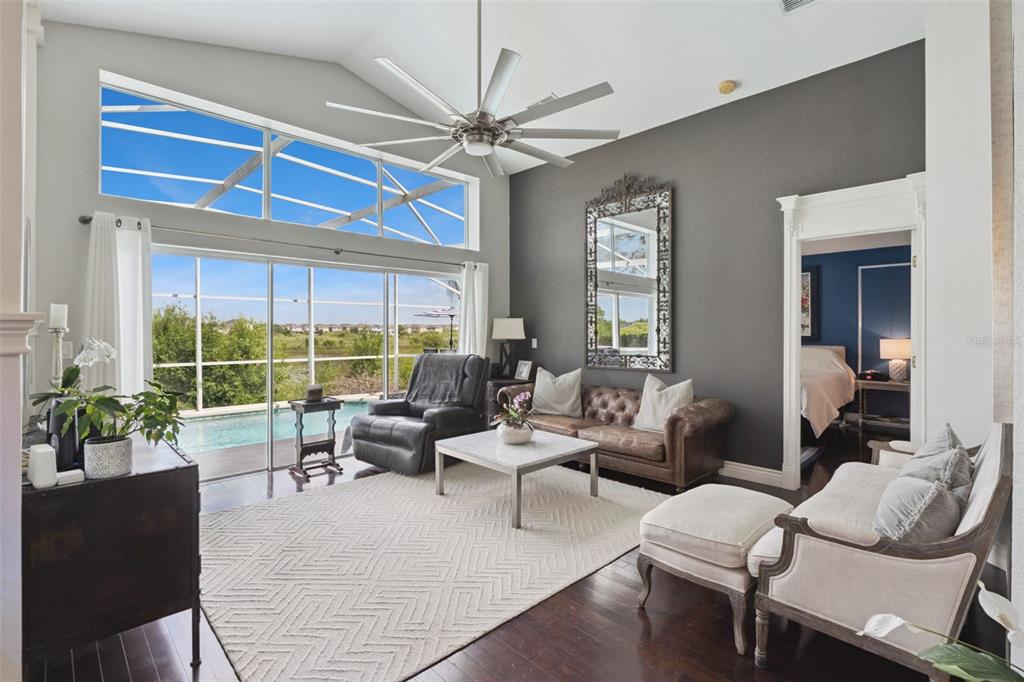 A living room with a vaulted ceiling, dark accent wall, leather sofa, and pool view — 112 WINDSOR PLACE, DAVENPORT, FL