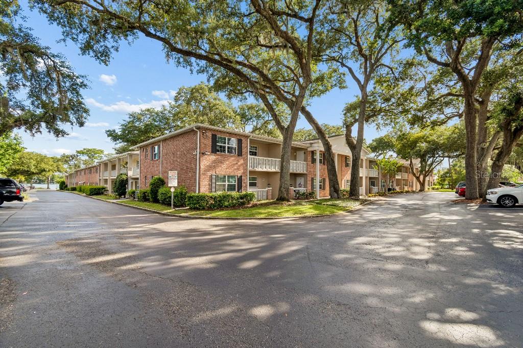 The exterior of a ground-level unit features a brick-accented porch, white railings, and a window — 2500 LEE ROAD UNIT 104, WINTER PARK, FL