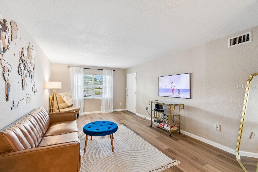 A dining room features a dark wood table, blue velvet chairs, and a brass chandelier — 2500 LEE ROAD UNIT 104, WINTER PARK, FL