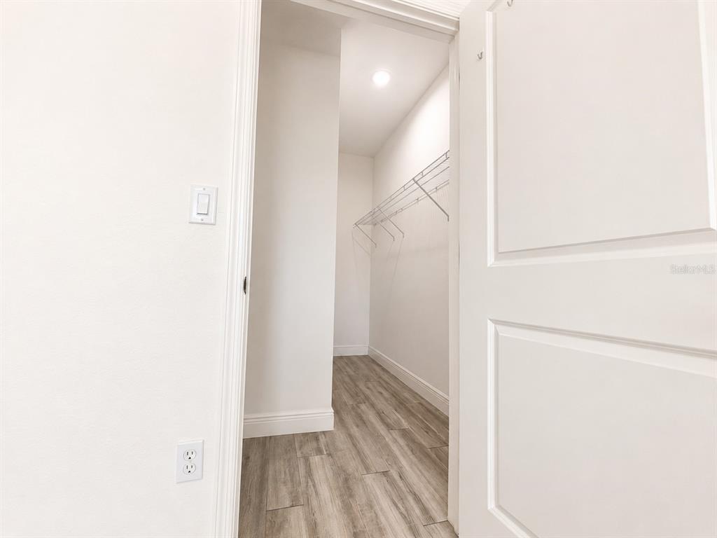 A view through a doorway into a walk-in closet with wire shelving and wood-look flooring — 3117 MEMPHIS LANE, LABELLE, FL