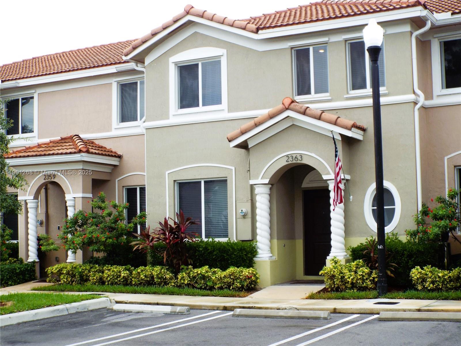 The exterior of a two-story townhouse features a tiled roof, arched entryways, and landscaping — 2363 SE 11th St, Homestead FL 33035, HOMESTEAD, FL