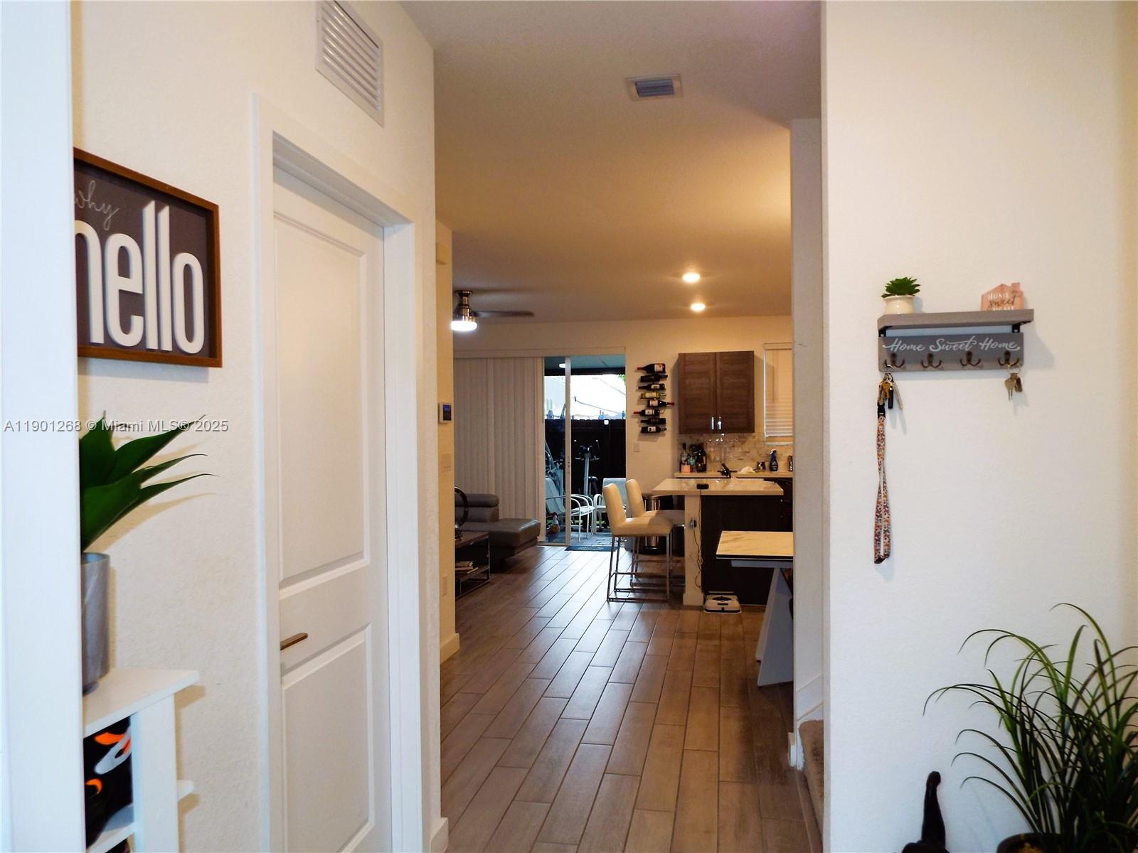 A view from a hallway looking into a kitchen and living area with wood-look flooring — 2363 SE 11th St, Homestead FL 33035, HOMESTEAD, FL