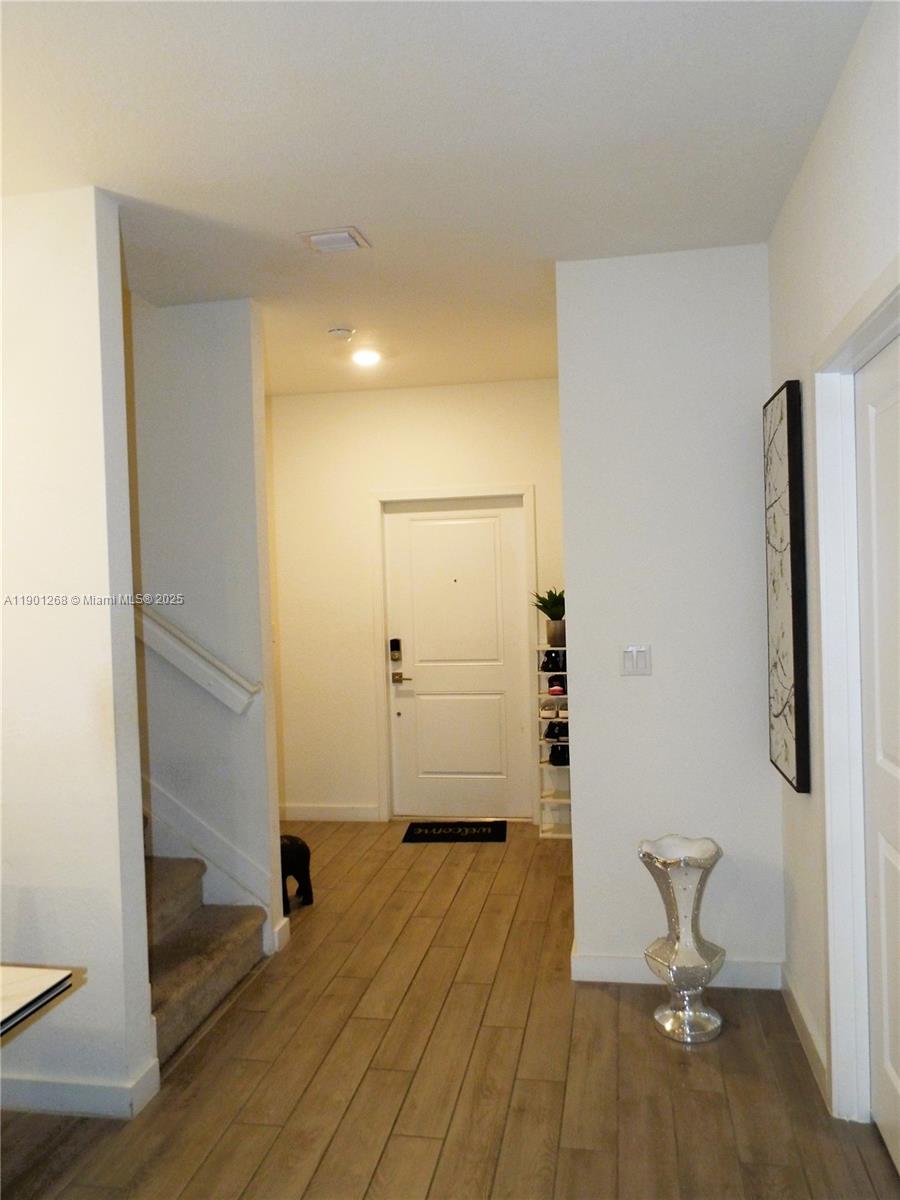 An entryway features wood-look tile flooring, a staircase with carpet, and a white front door — 2363 SE 11th St, Homestead FL 33035, HOMESTEAD, FL